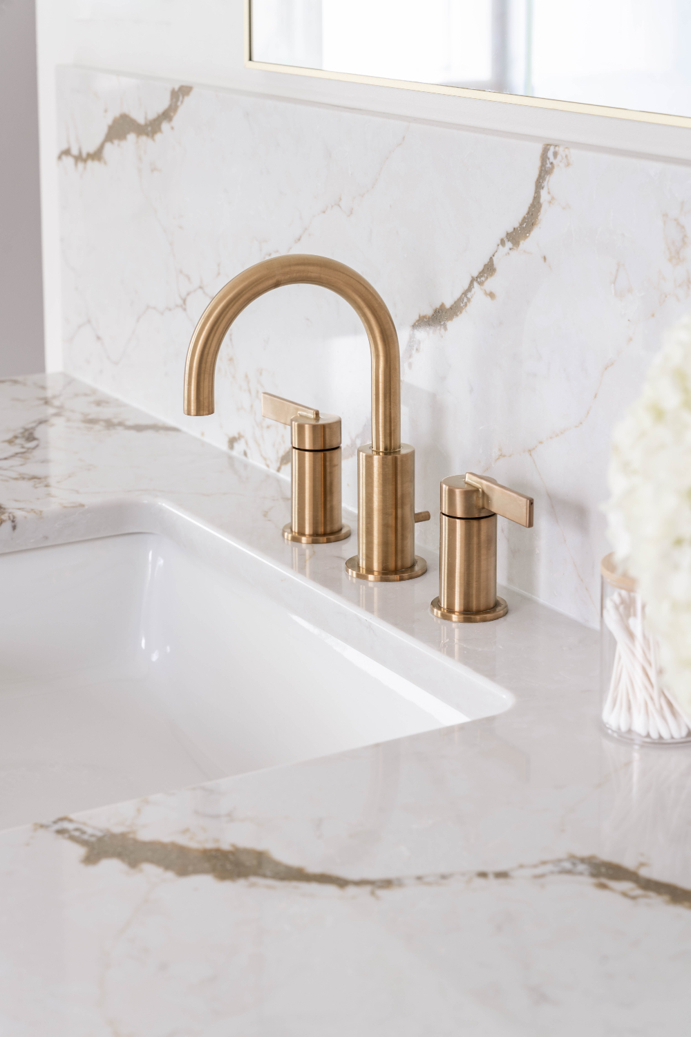 Luxury bathroom design in Omaha featuring brushed brass faucet, marble countertop, and custom backsplash detailing.