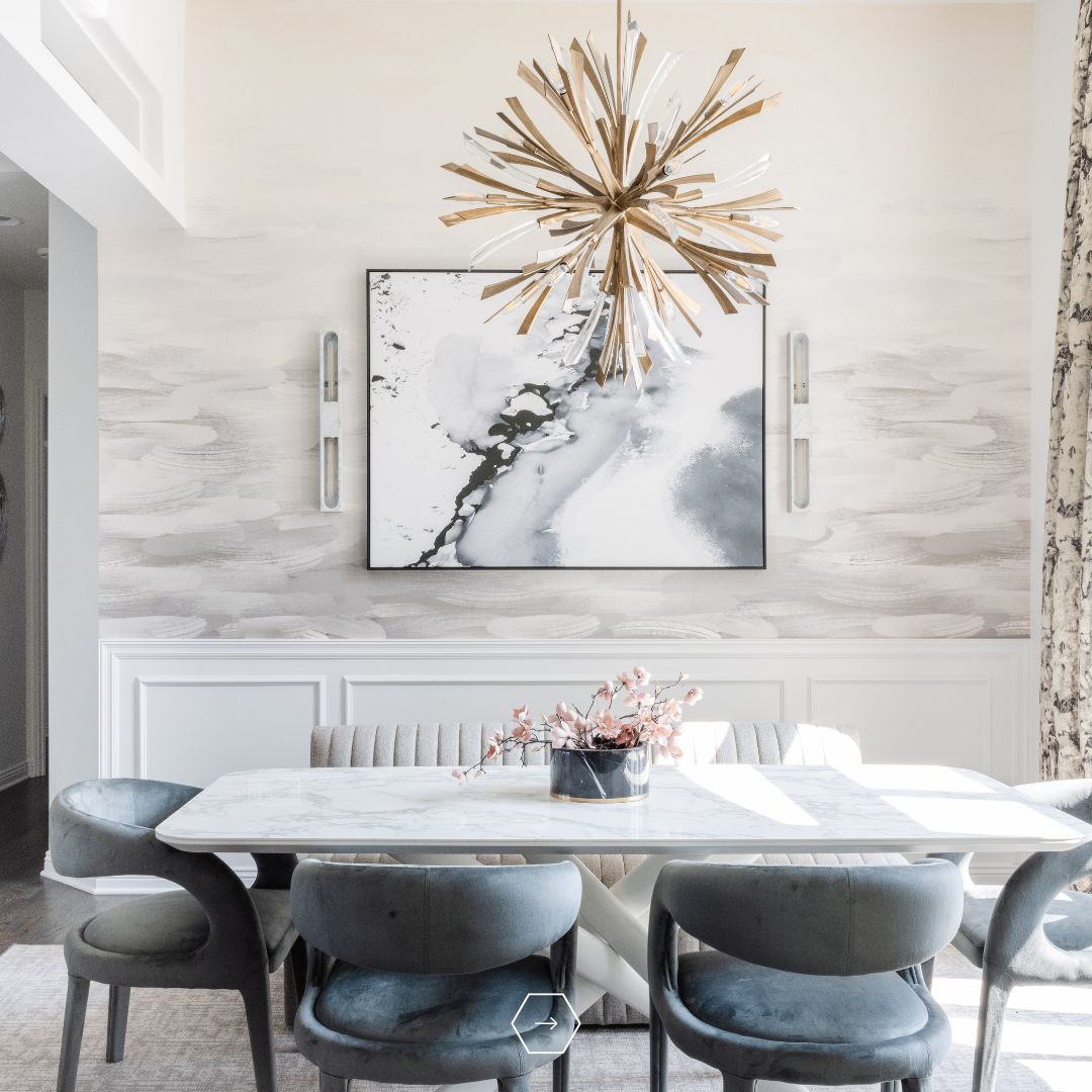 Modern dining room designed by an interior designer in Omaha featuring marble table, upholstered chairs, statement chandelier, and layered neutral finishes.
