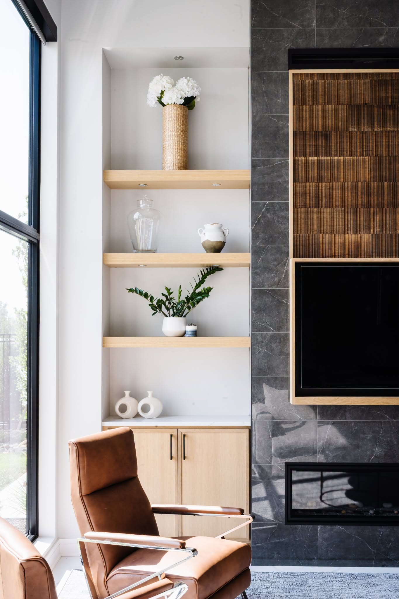 Living room by The Modern Hive with built-in oak shelving, curated decor, and a charcoal marble fireplace wall in an Omaha interior design project.